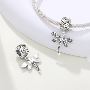 Makro-Detail eines silbernen Libellen-Charms mit gelben Steinen und Blattader-Textur