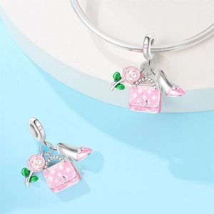 Detail of pink enamel charms featuring a handbag, rose, and high heel on a silver bracelet