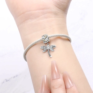 Detailansicht eines Libellen-Anhängers mit gelben Steinen auf einem Silberarmband