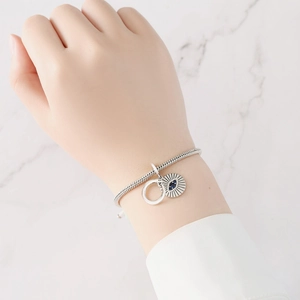Detailansicht eines silbernen Schlangenarmbands mit Evil-Eye-Anhänger am Handgelenk