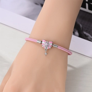 Rosa geflochtenes Armband mit Emaille Schleife und Sternanhänger am Handgelenk