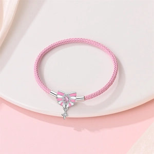Rosa geflochtenes Armband mit Schleifenanhänger und Stern auf weißem Keramiktablett