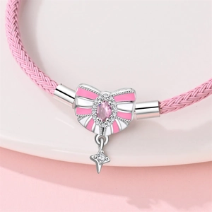 Makroaufnahme eines rosa Flechtarmbands mit silbernem Schleifenanhänger und Ziersteinen