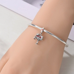 Detailed shot of silver charm bracelet featuring a cat sitting in a red enamel wine glass