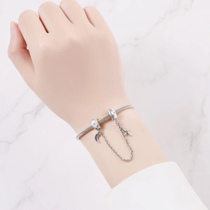 Silver snake chain bracelet with blue star and moon charms on marble background