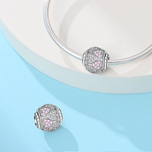 Macro detail of silver heart charms with pink and white cubic zirconia on a bracelet