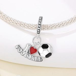 Macro shot of silver football charm with red enamel heart on a snake bone bracelet