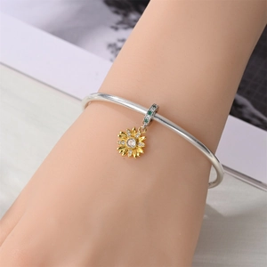 Close-up of silver bangle featuring gold sunflower charm with crystals on model wrist