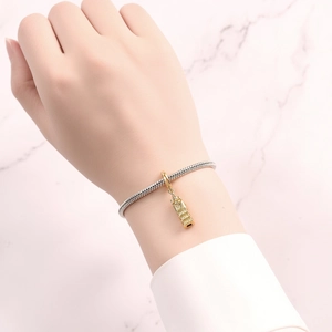 Silver snake chain bracelet with golden Big Ben charm shown on a wrist on marble