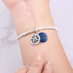 Makroaufnahme von Silber-Schlangenarmband mit Kompass-Anhänger und dunkelblauem Emaille