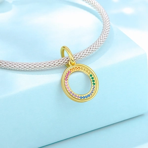 Detailed close-up of rainbow gemstone inlaid gold ring charm on silver mesh chain