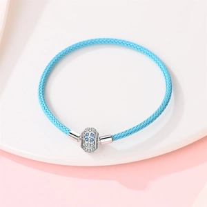 Nahaufnahme blaues Lederarmband mit silbernem Kleeblatt-Anhänger und blauen Kristallen