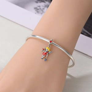 Detailed shot of a silver bracelet with a colorful angel charm and purple crystal accent