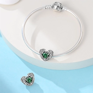Vue détaillée du bracelet en argent avec breloque cœur vert et textures de plumes