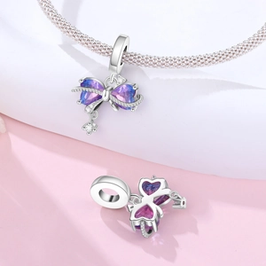 Makroaufnahme von Schleifen-Charm mit lila Herzstein und silbernem Armband-Detail