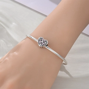 Gros plan d'un bracelet argenté avec un pendentif en forme de cœur et cristaux roses