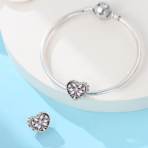 Vue détaillée des breloques cœur et bracelet à maille serpent avec gemmes roses