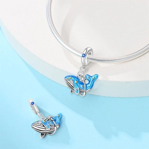 Macro detail of blue whale charm with gold stars and zircon on a silver snake chain