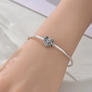 Détail d'un bracelet à breloques argenté avec pendentif en cœur et pierres précieuses