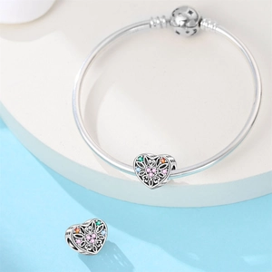 Détail macro du bracelet argenté avec des perles creuses gravées en forme de cœur