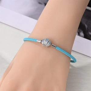 Nahaufnahme eines hellblauen geflochtenen Armbands mit silbernem Muschel-Anhänger am Handgelenk
