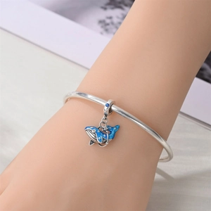 Silver open bangle with a blue enamel whale charm featuring gold stars and zircon