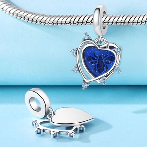Close-up of heart charm with bee motif and blue stones on silver snake chain