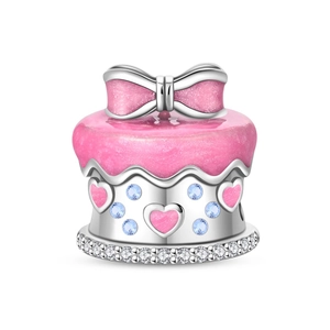 Macro detail of silver cake charm with pink bow, heart patterns and blue zircon inlay