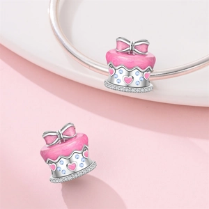 Macro shot of pink enamel birthday cake charm with blue zircons for DIY bracelets