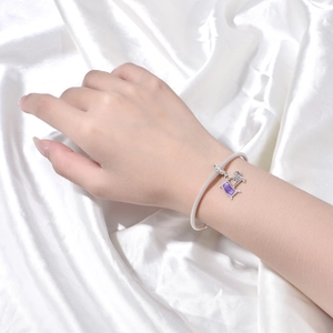 Detalle de pulsera de malla plateada con lentejuelas moradas y colgantes de caballo en seda