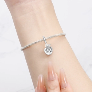 Nahaufnahme eines silbernen Apfel-Anhängers mit Zirkonia am Schlangen-Armband