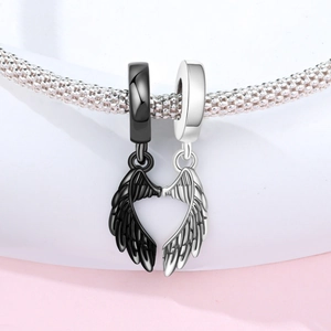 Detail of silver and black angel wing charms on a snake chain forming a heart shape