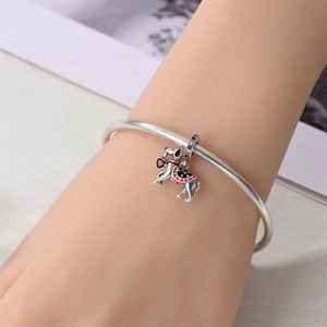 Close-up of a silver charm bracelet with an enamel horse pendant and pink heart gem
