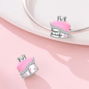 Macro detail of silver crown cake charm with pink enamel hearts and Happy Birthday engraving