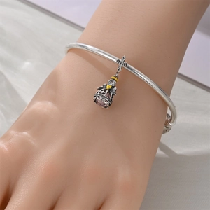 Silver open bangle featuring a vintage pendant with purple gemstone and cross charm