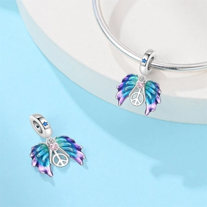 Detailed macro of silver peace sign charm with gradient wings and pink heart stone