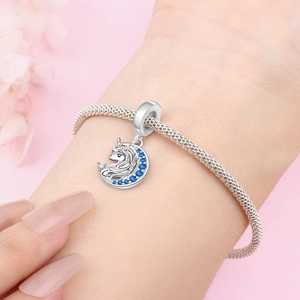 Detailed view of silver unicorn and crescent moon charm set with blue crystals on a bracelet