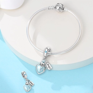 Vue macro du charme coeur avec étiquette Mojo et gemme bleue sur bracelet chaîne argent