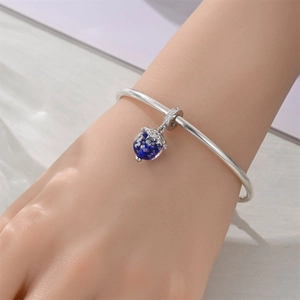 Detail of silver plated bracelet with a deep blue starry globe charm on a model's wrist