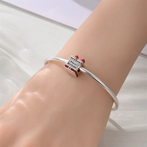 Close-up of birthday gift box charm with red enamel bow and Happy Birthday engraving