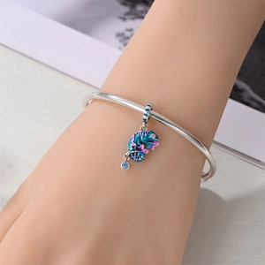 Detail of silver bangle with a colorful enamel chameleon charm and blue zircon stones