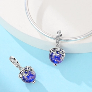 Macro detail of silver charm featuring a glowing blue celestial globe with stars