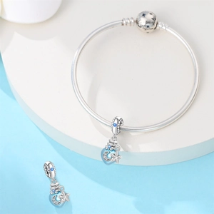 Detail of silver snake chain bracelet with blue enamel moon and star charms and engraving