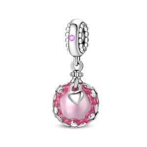 Vue macro d'une breloque cœur rose avec motif évidé en argent et pierre précieuse