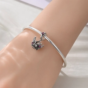 Close-up of crown charm with pink and white cubic zirconia on silver bracelet