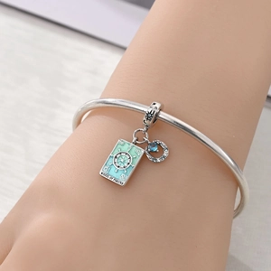 Macro shot of silver charm bracelet with Wheel of Fortune tarot and crescent moon charms