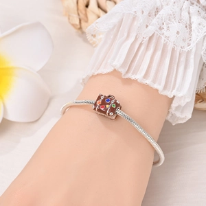 Close-up of silver snake chain bracelet with brown vintage suitcase charm on wrist