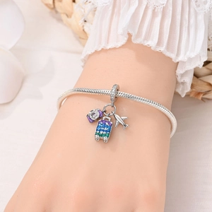Close-up of silver travel charms including camera, airplane and luggage on snake chain