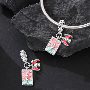Macro detail of Temperance tarot charm with enamel wings and pink crystals on silver