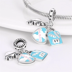 Macro detail of silver travel charms with car, earth heart and blue suitcase on snake chain